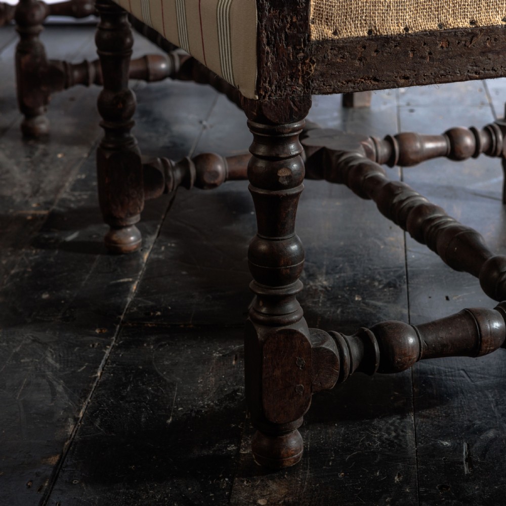 A 17th century wingback sofa featuring striped upholstery, exposed jute side panels, turned wooden legs, and stretchers. View VIII