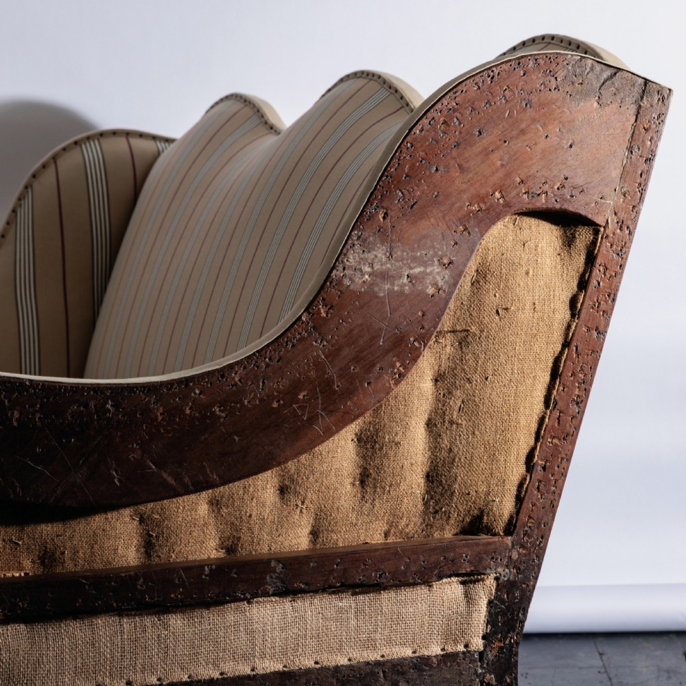 A 17th century wingback sofa featuring striped upholstery, exposed jute side panels, turned wooden legs, and stretchers. View XIV