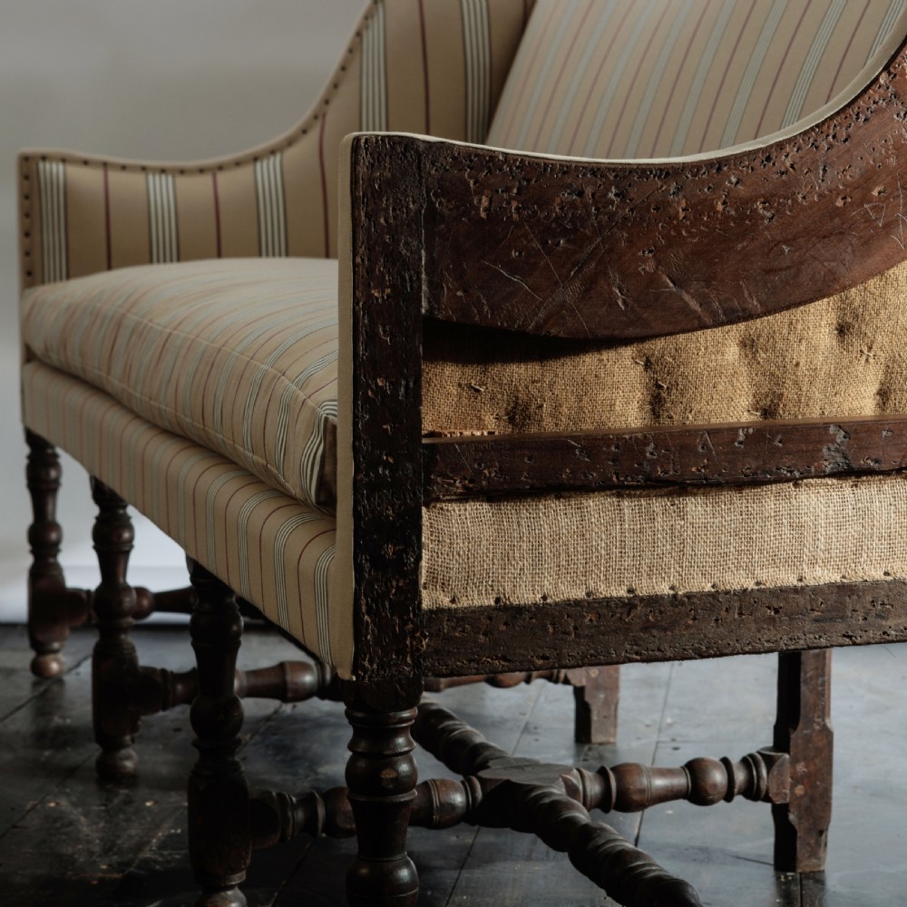 A 17th century wingback sofa featuring striped upholstery, exposed jute side panels, turned wooden legs, and stretchers. View XVI