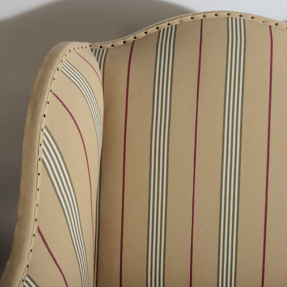 A 17th century wingback sofa featuring striped upholstery, exposed jute side panels, turned wooden legs, and stretchers. View XXII
