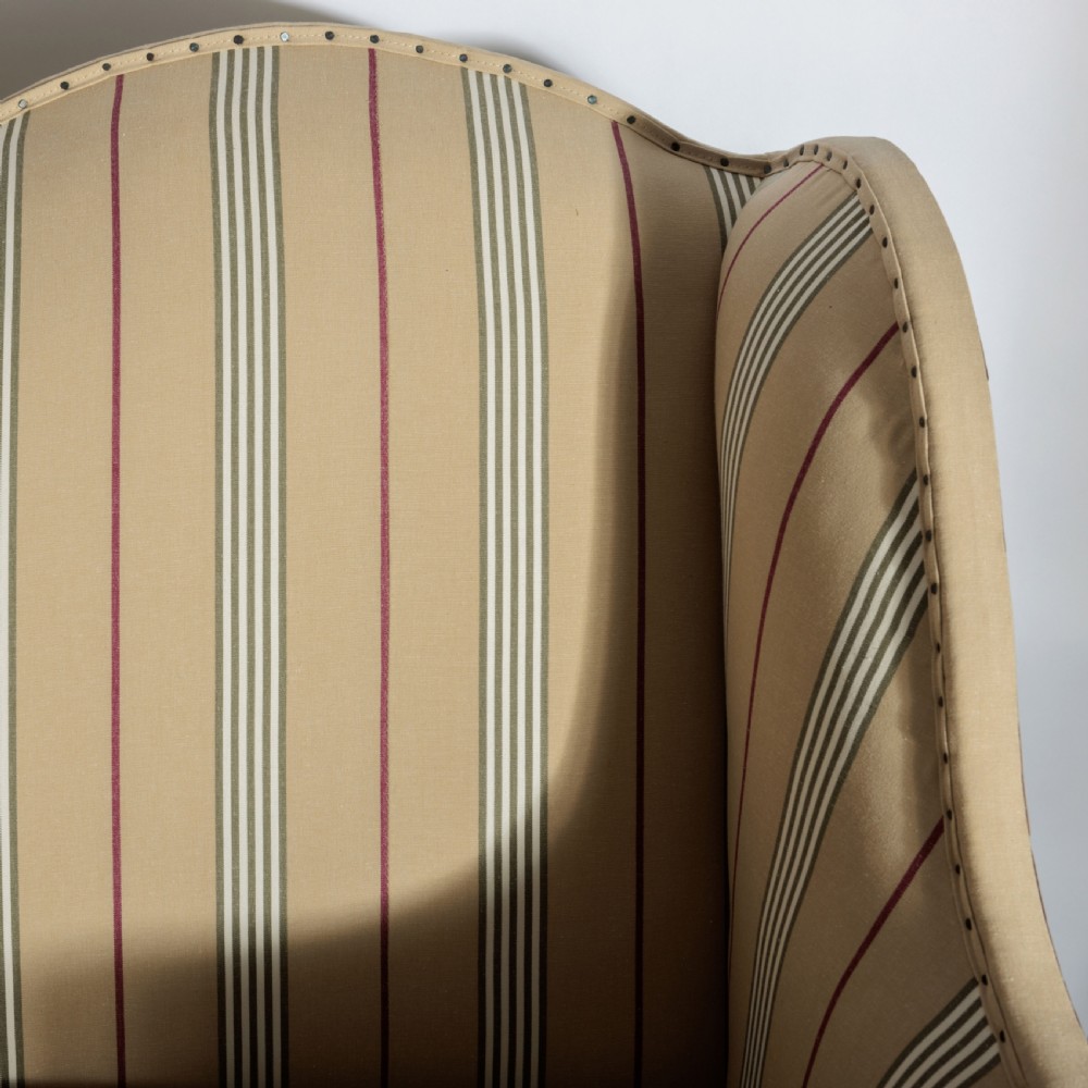 A 17th century wingback sofa featuring striped upholstery, exposed jute side panels, turned wooden legs, and stretchers. View XXIII