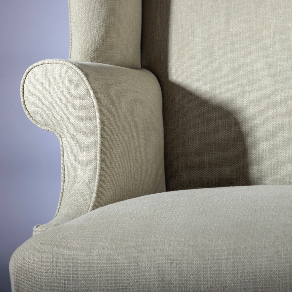 An 18th-century Georgian style wingback armchair upholstered in neutral cream linen, supported by dark square timber legs with H-stretchers. View II