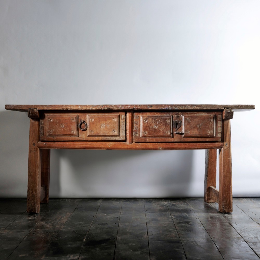 An 18th-century Spanish wooden console table featuring two carved drawer fronts with iron handles and a thick timber top.