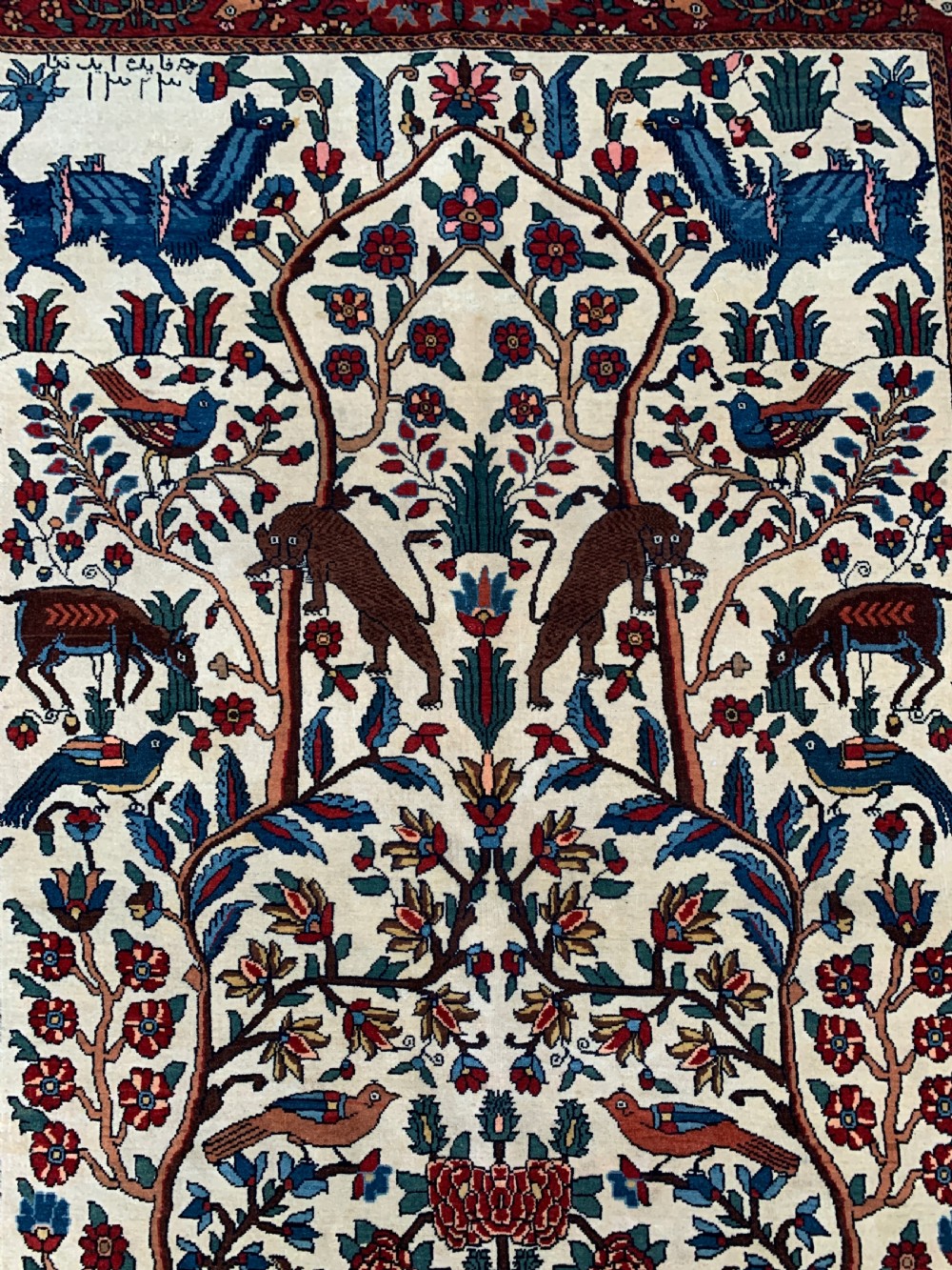 A hand-knotted Persian Sarouk wool rug featuring a central Tree of Life design populated with birds and animals on a cream field framed by a deep red floral border. View V