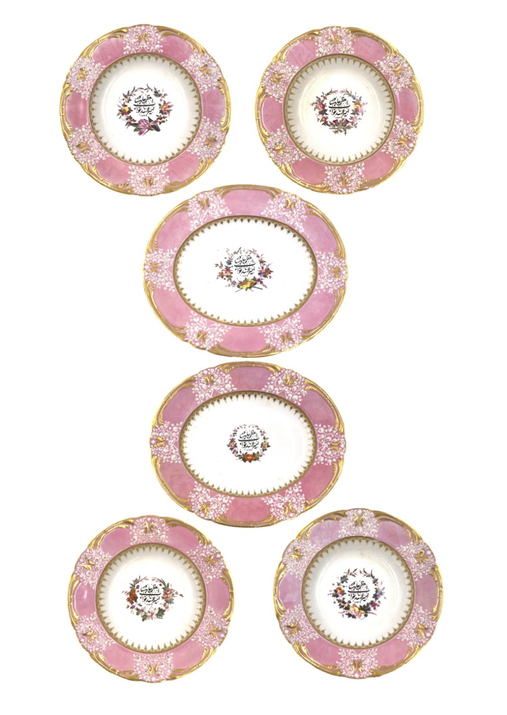 A set of six Regency porcelain plates and platters with rose pink borders, burnished gilding, and central script inscriptions framed by floral wreaths.