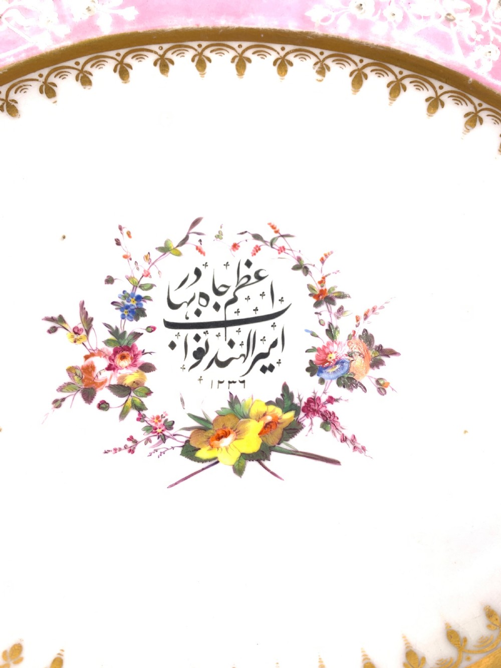 A set of six Regency porcelain plates and platters with rose pink borders, burnished gilding, and central script inscriptions framed by floral wreaths. View III