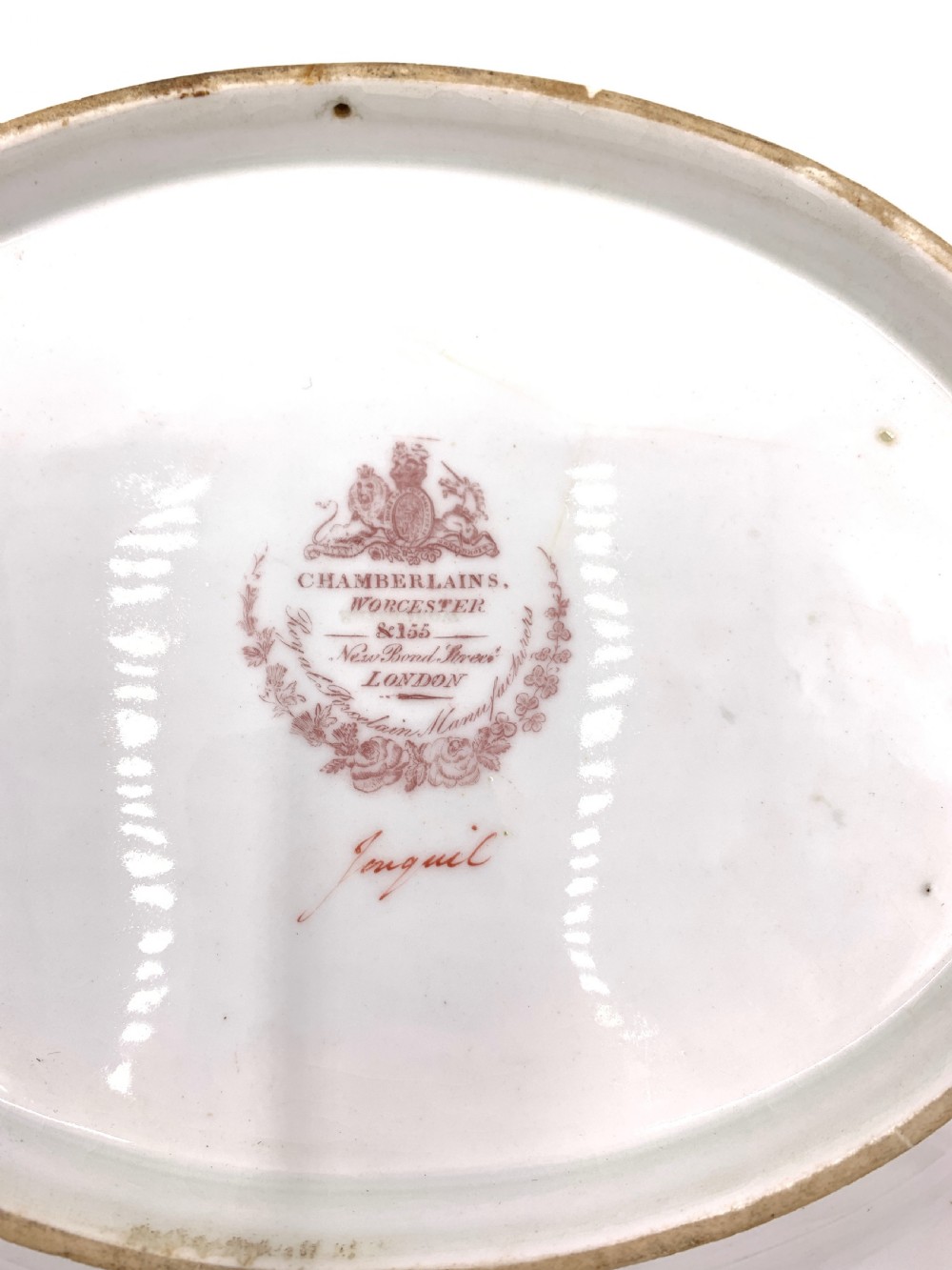 A set of six Regency porcelain plates and platters with rose pink borders, burnished gilding, and central script inscriptions framed by floral wreaths. View IV