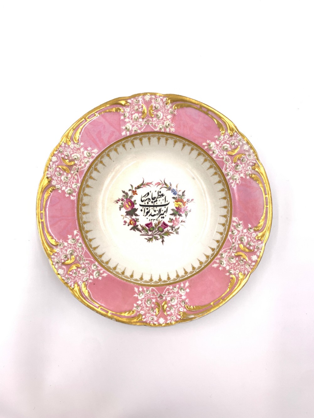A set of six Regency porcelain plates and platters with rose pink borders, burnished gilding, and central script inscriptions framed by floral wreaths. View VIII