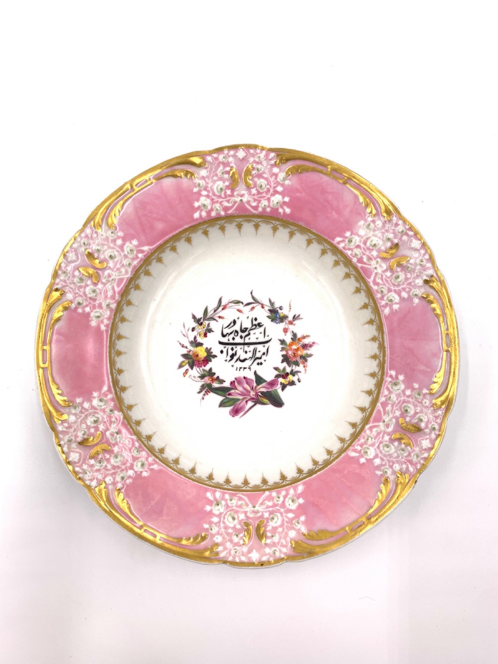 A set of six Regency porcelain plates and platters with rose pink borders, burnished gilding, and central script inscriptions framed by floral wreaths. View XI