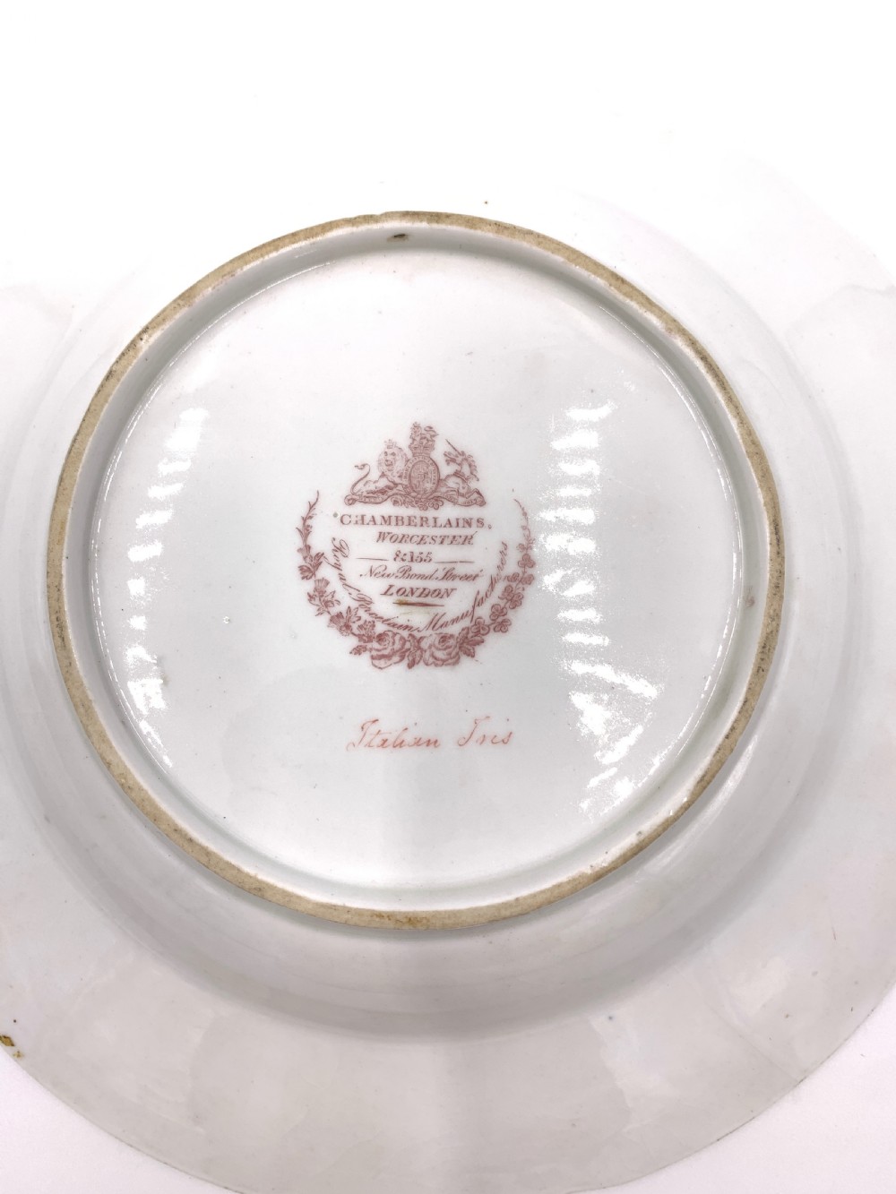 A set of six Regency porcelain plates and platters with rose pink borders, burnished gilding, and central script inscriptions framed by floral wreaths. View XIII