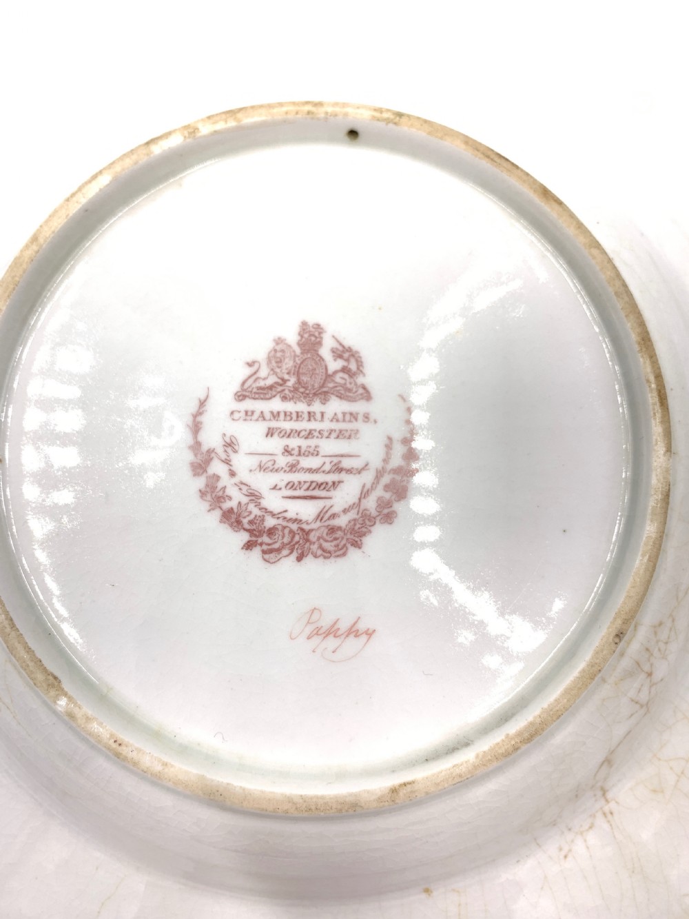 A set of six Regency porcelain plates and platters with rose pink borders, burnished gilding, and central script inscriptions framed by floral wreaths. View XVI