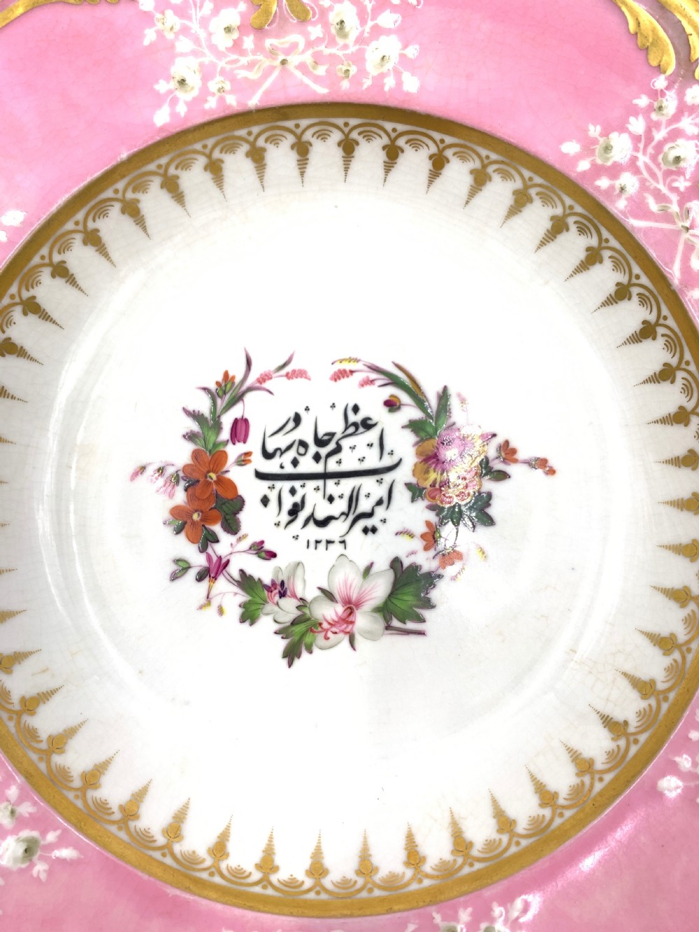 A set of six Regency porcelain plates and platters with rose pink borders, burnished gilding, and central script inscriptions framed by floral wreaths. View XVIII