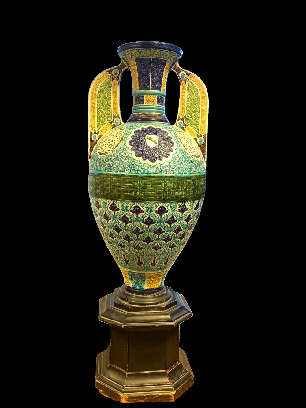 A tall 19th-century Alhambra-style ceramic vase featuring winged handles, arabesque relief decoration, and turquoise and cobalt glazes on an octagonal black base. View III