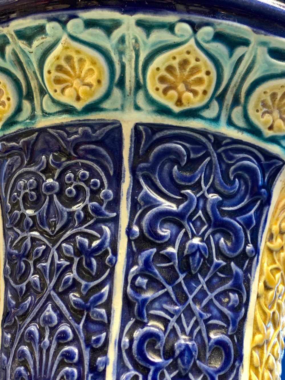 A tall 19th-century Alhambra-style ceramic vase featuring winged handles, arabesque relief decoration, and turquoise and cobalt glazes on an octagonal black base. View IV