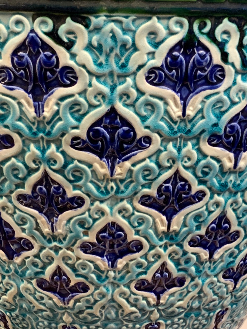 A tall 19th-century Alhambra-style ceramic vase featuring winged handles, arabesque relief decoration, and turquoise and cobalt glazes on an octagonal black base. View VI