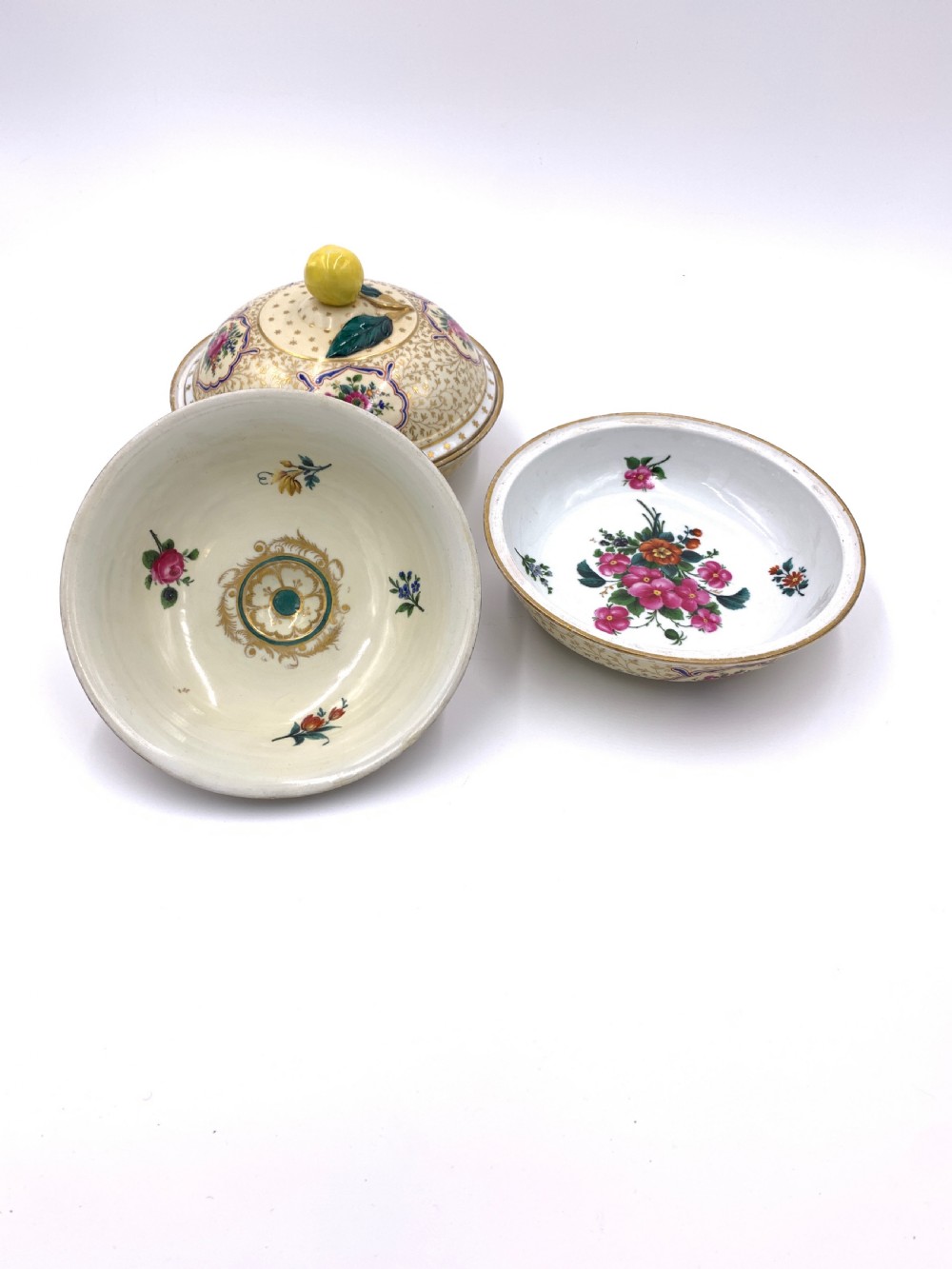 A pair of circular porcelain bonbonnieres featuring cream ground with gold leaf scrollwork, hand-painted floral cartouches, and sculpted lemon finials on the lids. View IV