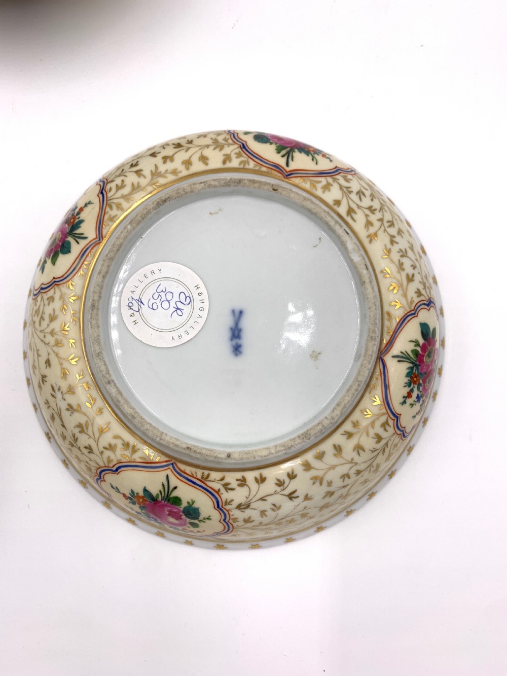 A pair of circular porcelain bonbonnieres featuring cream ground with gold leaf scrollwork, hand-painted floral cartouches, and sculpted lemon finials on the lids. View V