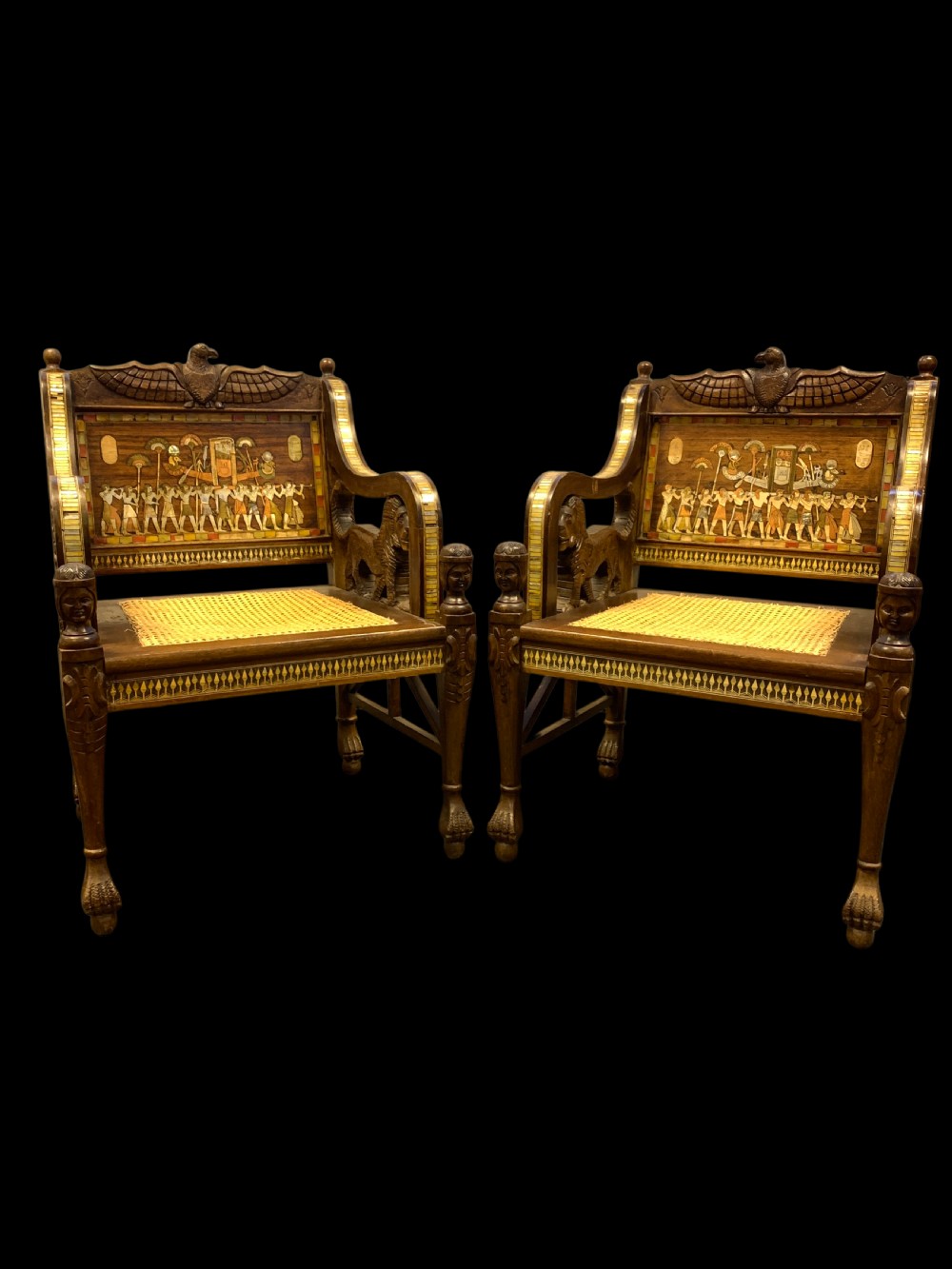 A three-piece nineteenth-century Egyptian Revival furniture suite consisting of a settee and two armchairs with carved winged crestings, figural marquetry backrests, and cane seats. View II