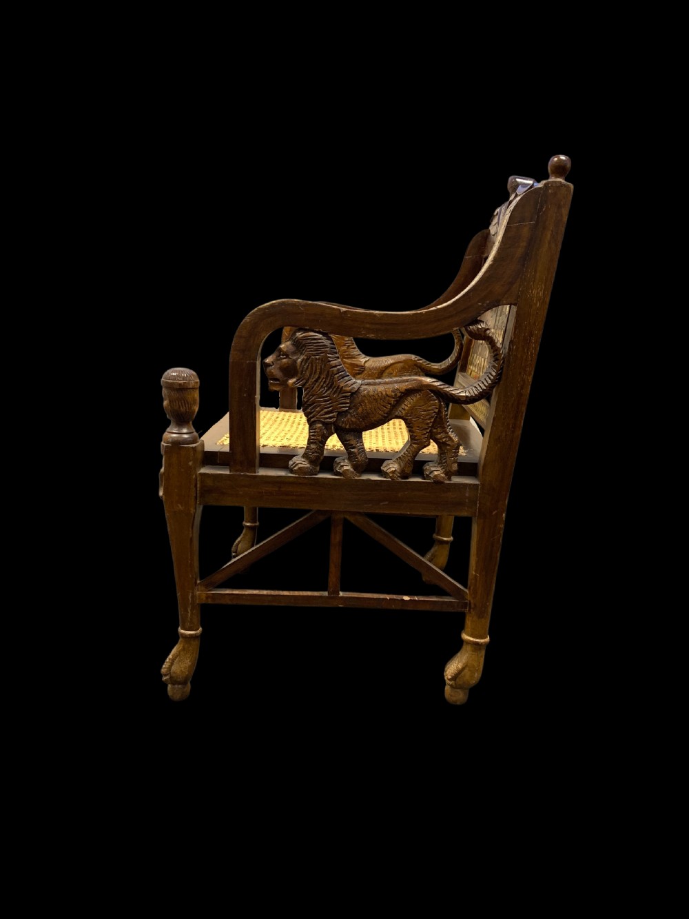 A three-piece nineteenth-century Egyptian Revival furniture suite consisting of a settee and two armchairs with carved winged crestings, figural marquetry backrests, and cane seats. View IV
