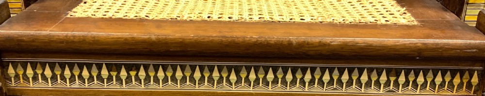 A three-piece nineteenth-century Egyptian Revival furniture suite consisting of a settee and two armchairs with carved winged crestings, figural marquetry backrests, and cane seats. View X
