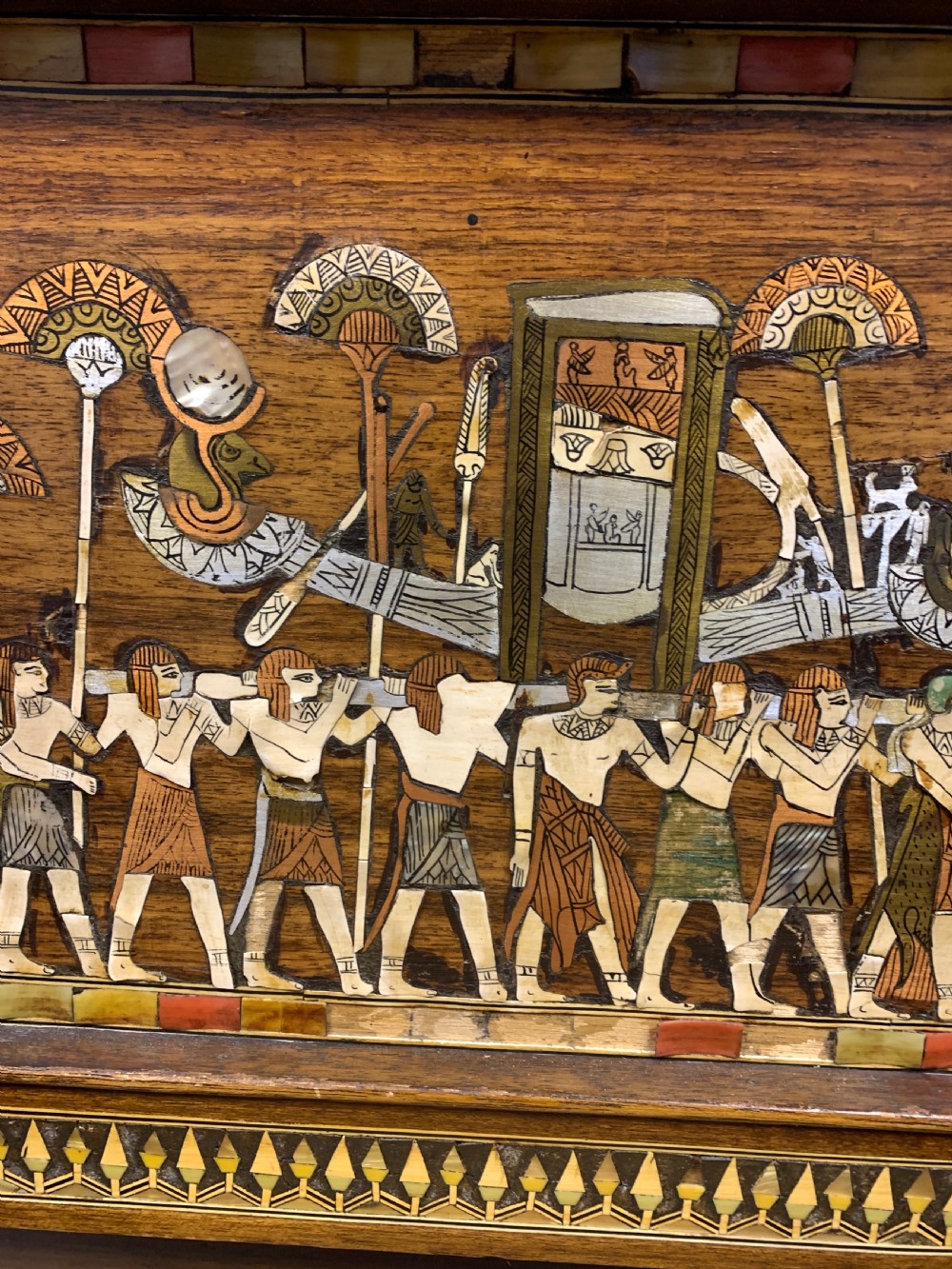 A three-piece nineteenth-century Egyptian Revival furniture suite consisting of a settee and two armchairs with carved winged crestings, figural marquetry backrests, and cane seats. View XV