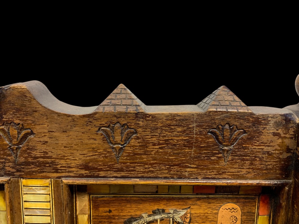 A three-piece nineteenth-century Egyptian Revival furniture suite consisting of a settee and two armchairs with carved winged crestings, figural marquetry backrests, and cane seats. View XXIII