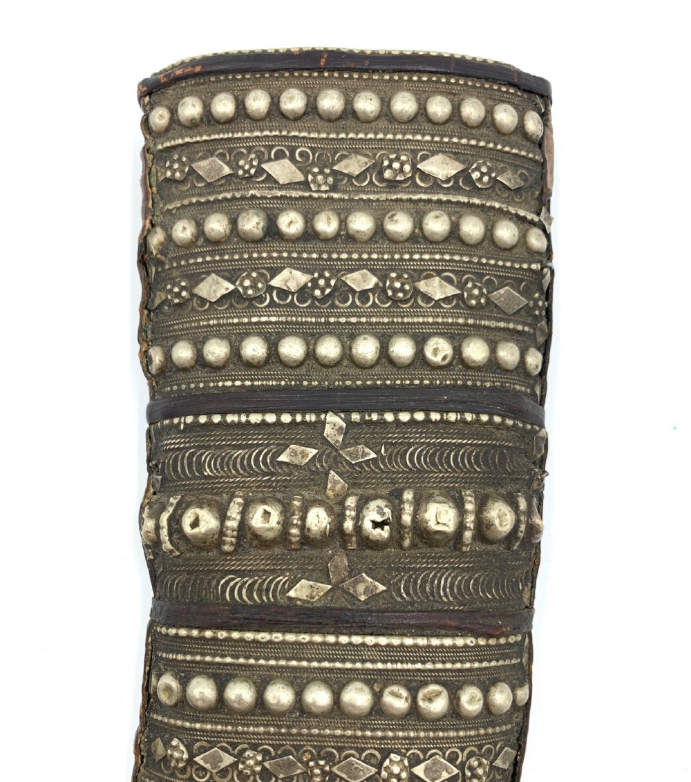 A curved Yemeni jambiya dagger in an intricately decorated silver sheath with a matching silver-mounted hilt. View V