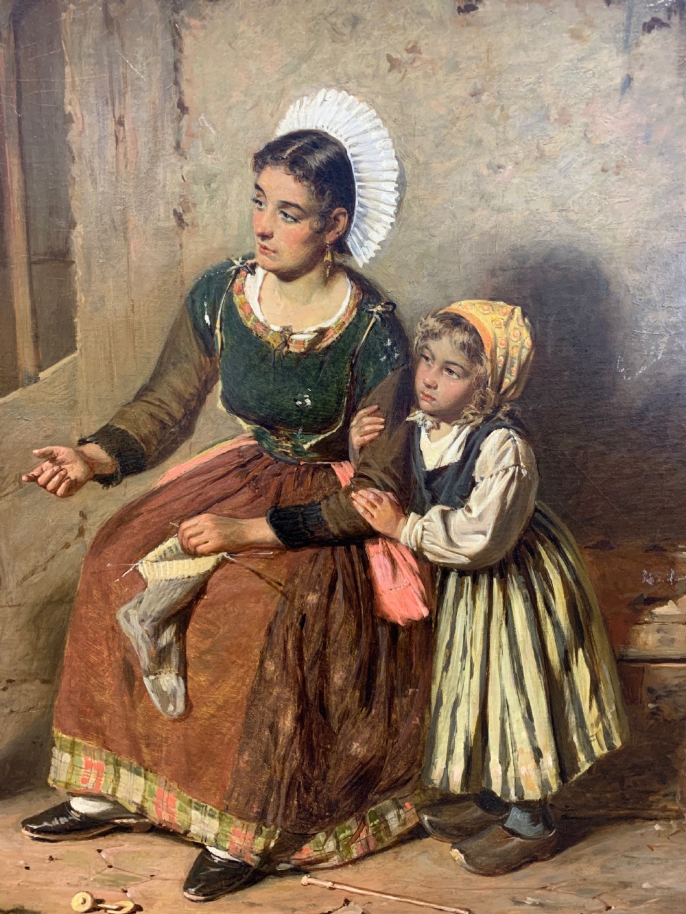 An antique oil painting depicting a mother and two children in a rustic interior, enclosed within an ornate gilded frame. View III
