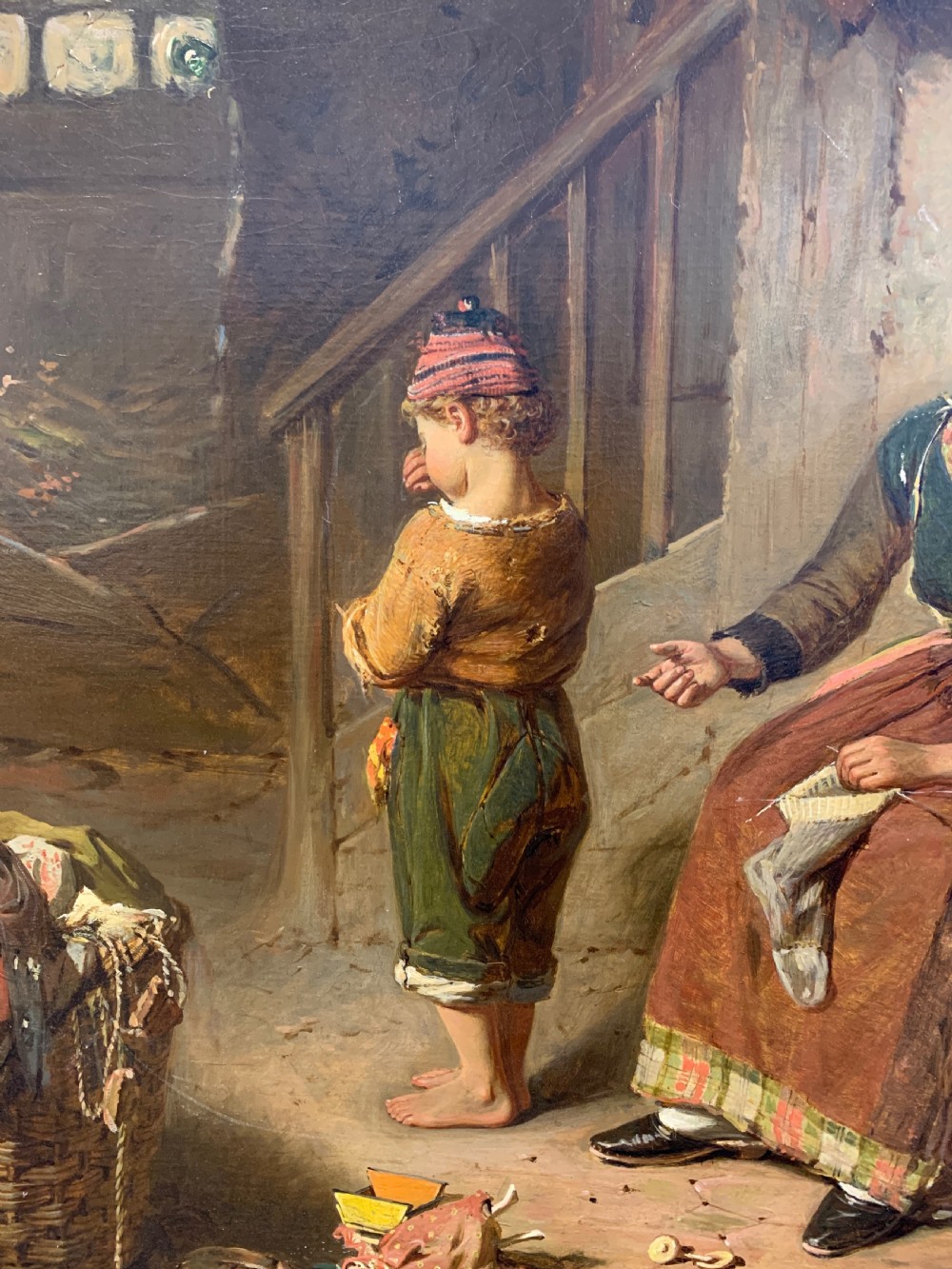 An antique oil painting depicting a mother and two children in a rustic interior, enclosed within an ornate gilded frame. View IV