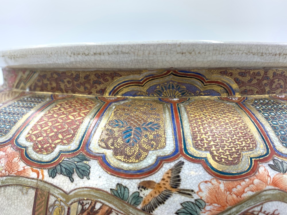 A large bulbous Japanese Satsuma earthenware bowl featuring intricate polychrome enamel scenes of figures in traditional attire, bordered by elaborate gilt geometric patterns on a crackled cream ground. View VIII