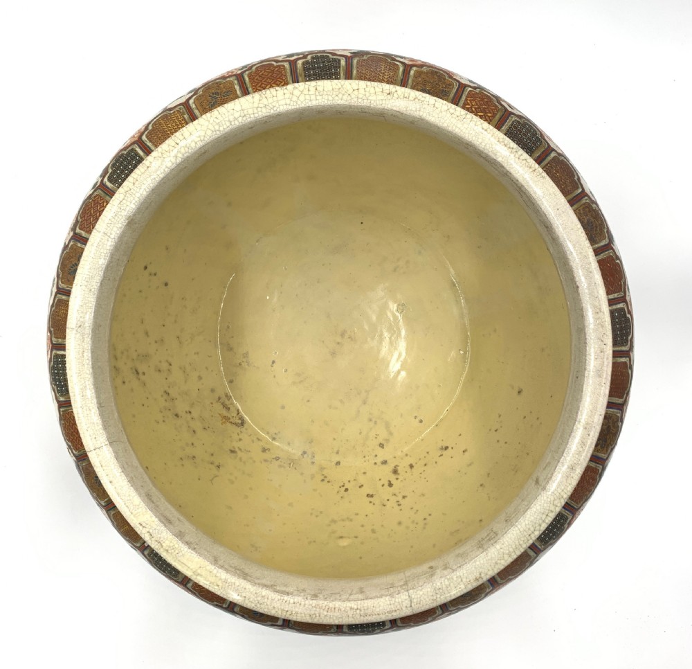 A large bulbous Japanese Satsuma earthenware bowl featuring intricate polychrome enamel scenes of figures in traditional attire, bordered by elaborate gilt geometric patterns on a crackled cream ground. View IX