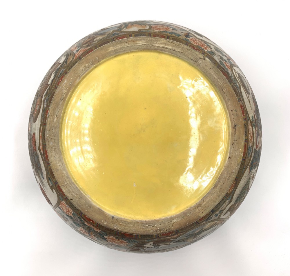 A large bulbous Japanese Satsuma earthenware bowl featuring intricate polychrome enamel scenes of figures in traditional attire, bordered by elaborate gilt geometric patterns on a crackled cream ground. View X