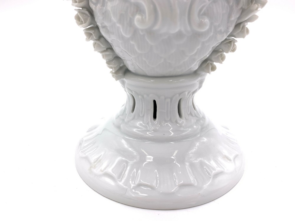 A white glazed porcelain urn featuring applied floral garlands, a pedestal base, and a pierced lid topped with a rose finial. View IV