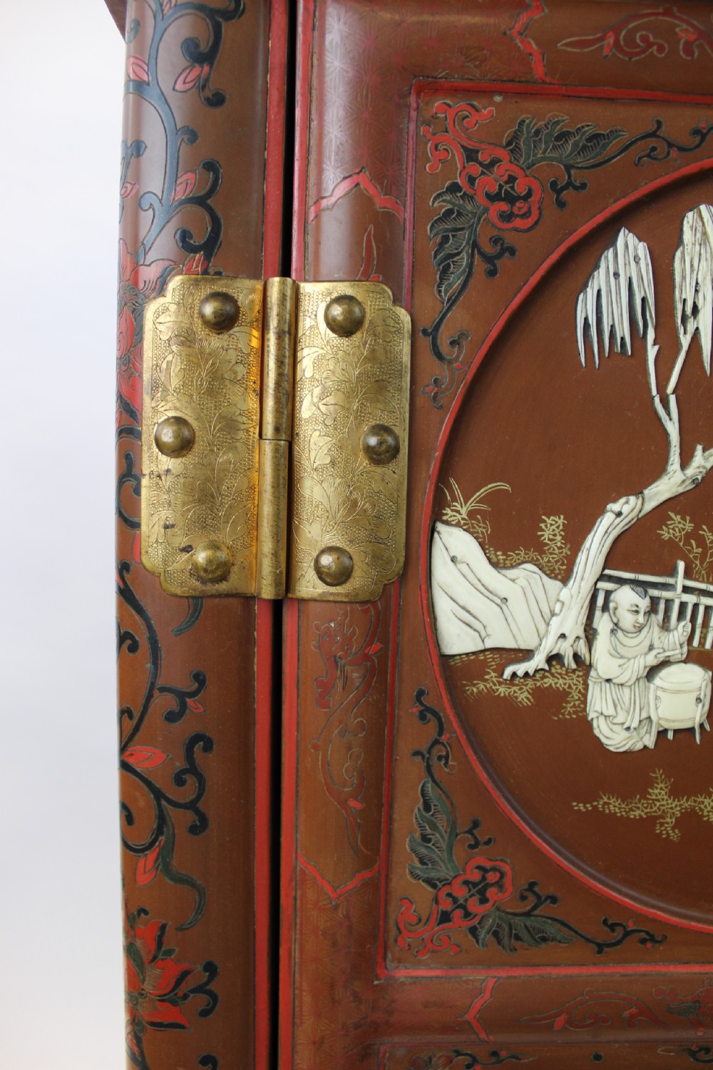 A 19th-century Chinese red lacquer cabinet featuring two doors decorated with carved white relief panels depicting figures, birds, and botanical motifs, fitted with brass lockplates. View XIII