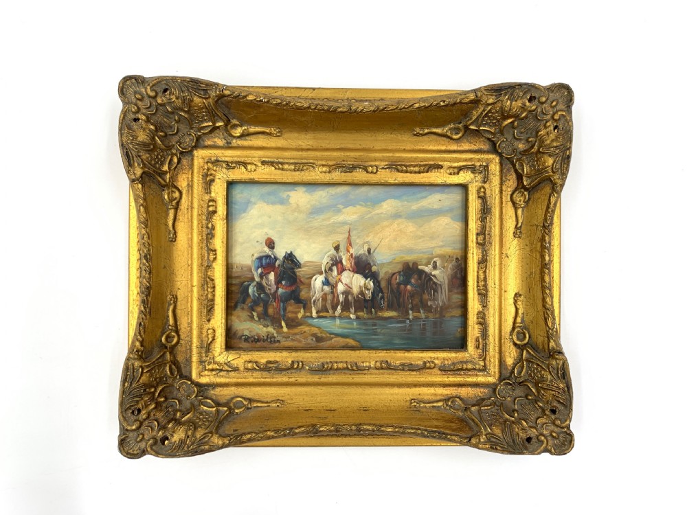 A pair of framed Orientalist oil paintings on board in heavily ornamented gold gilt frames, depicting Middle Eastern figures indoors and riders watering horses outdoors. View II