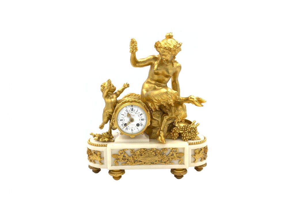 A late nineteenth-century French Louis XVI style gilt-bronze and white marble mantel clock featuring a sculptural bacchante figure alongside an enamel dial.
