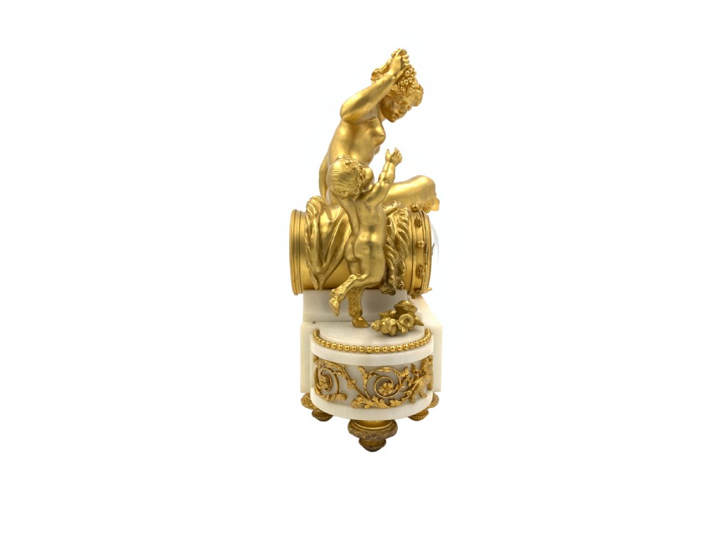 A late nineteenth-century French Louis XVI style gilt-bronze and white marble mantel clock featuring a sculptural bacchante figure alongside an enamel dial. View IV