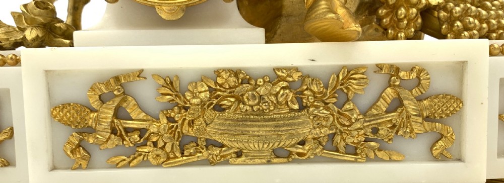 A late nineteenth-century French Louis XVI style gilt-bronze and white marble mantel clock featuring a sculptural bacchante figure alongside an enamel dial. View XIII