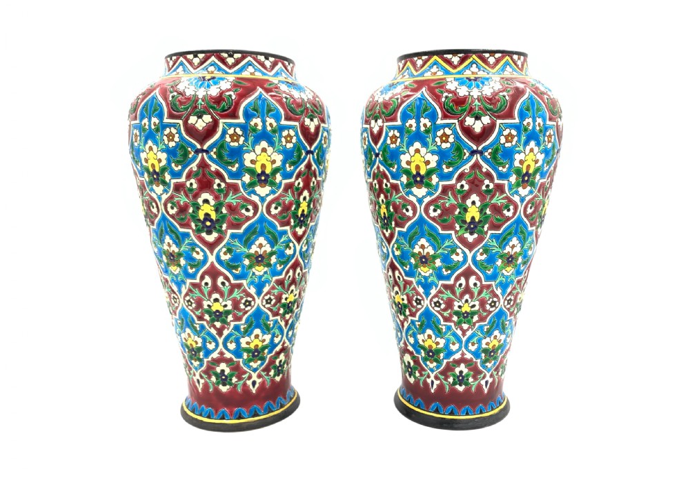 A pair of baluster-shaped French faience vases decorated with vibrant blue, crimson, and yellow enamelled floral arabesque patterns.