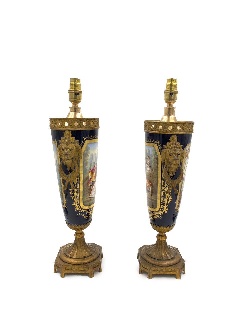 A pair of French Sevres style cobalt blue porcelain table lamps featuring hand-painted romantic scenes, gilt bronze handles, and pleated cream fabric shades. View III