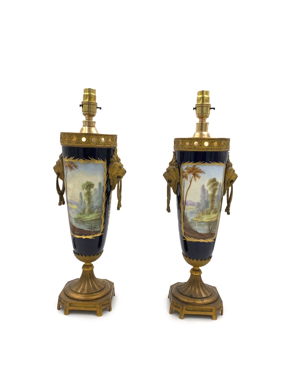 A pair of French Sevres style cobalt blue porcelain table lamps featuring hand-painted romantic scenes, gilt bronze handles, and pleated cream fabric shades. View VII