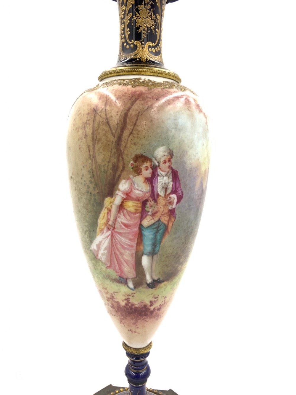 A 19th-century French Sevres style porcelain urn table lamp featuring hand-painted figures, cobalt blue accents, gilt detail, and a pleated silk shade. View V