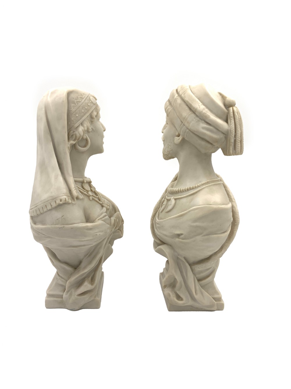 A pair of carved off-white marble busts depicting a man and woman in detailed Orientalist dress and headwear on integral square bases. View II