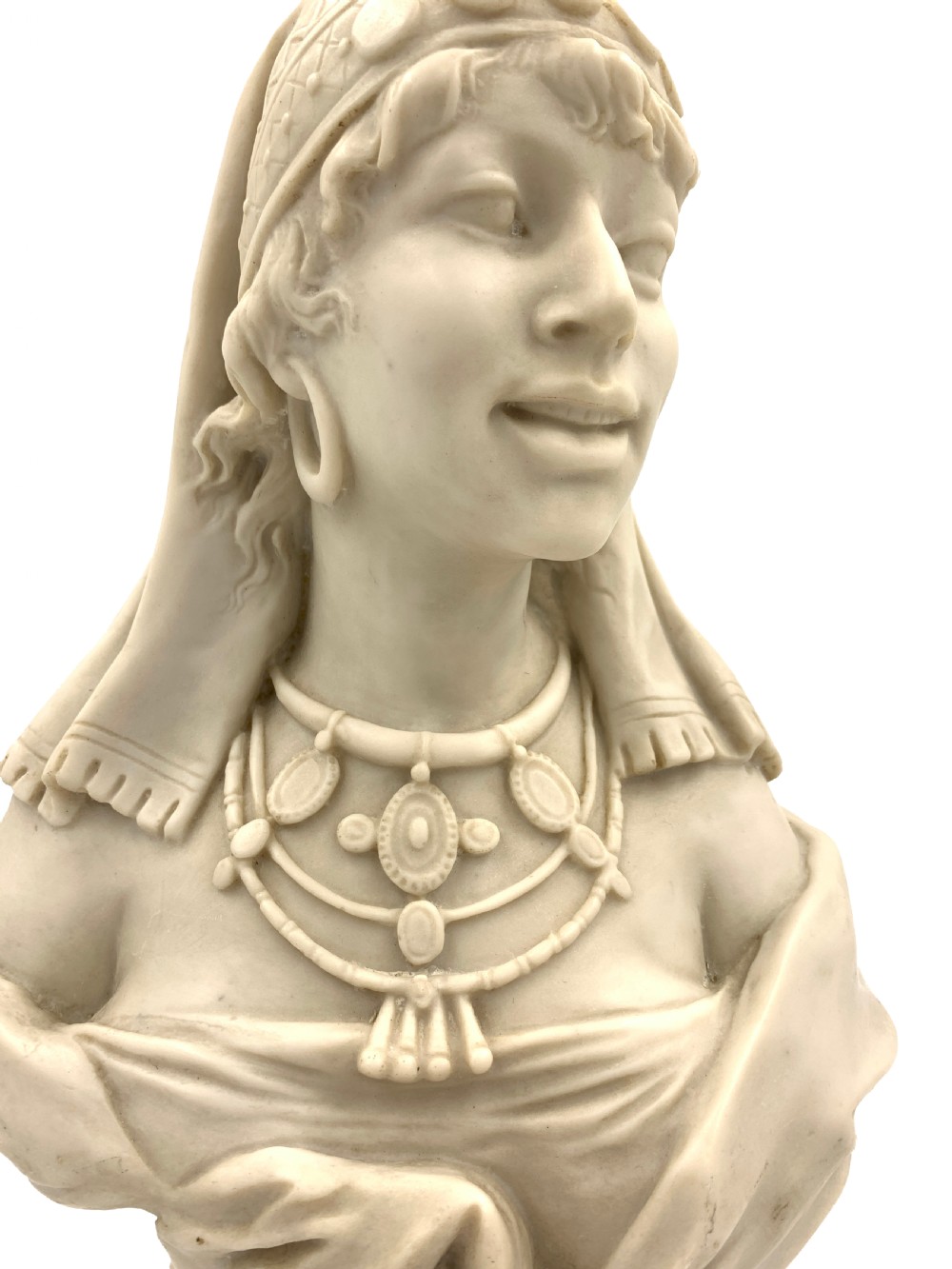 A pair of carved off-white marble busts depicting a man and woman in detailed Orientalist dress and headwear on integral square bases. View V