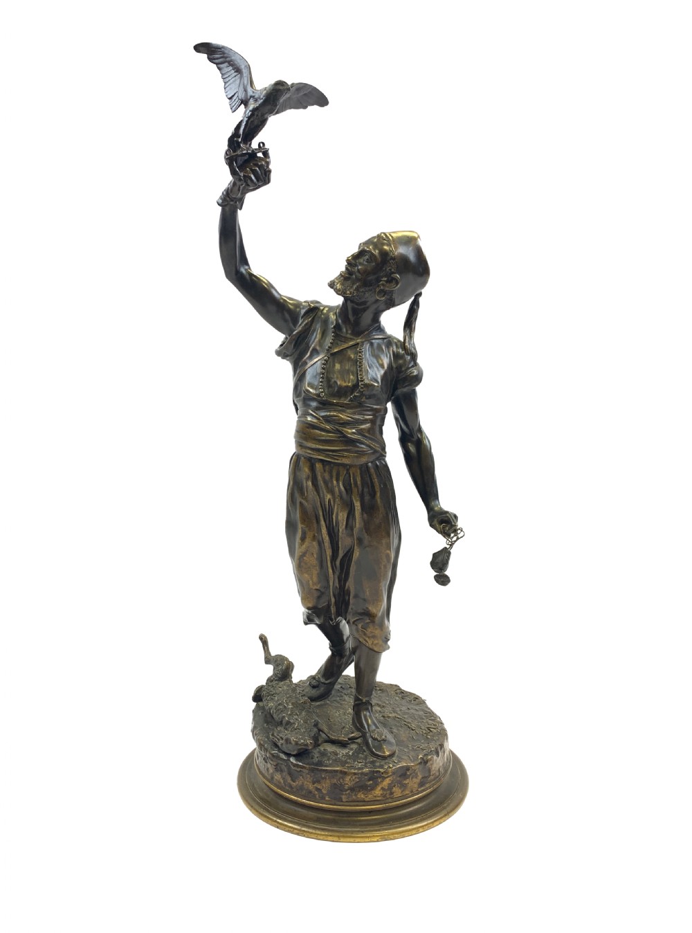 A dark brown patinated bronze sculpture depicting an Arab falconer holding a falcon overhead while standing on a circular base.
