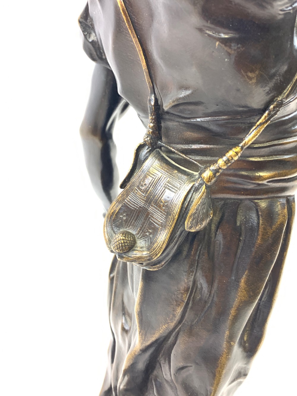 A dark brown patinated bronze sculpture depicting an Arab falconer holding a falcon overhead while standing on a circular base. View IV