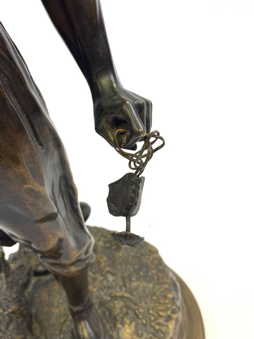 A dark brown patinated bronze sculpture depicting an Arab falconer holding a falcon overhead while standing on a circular base. View X