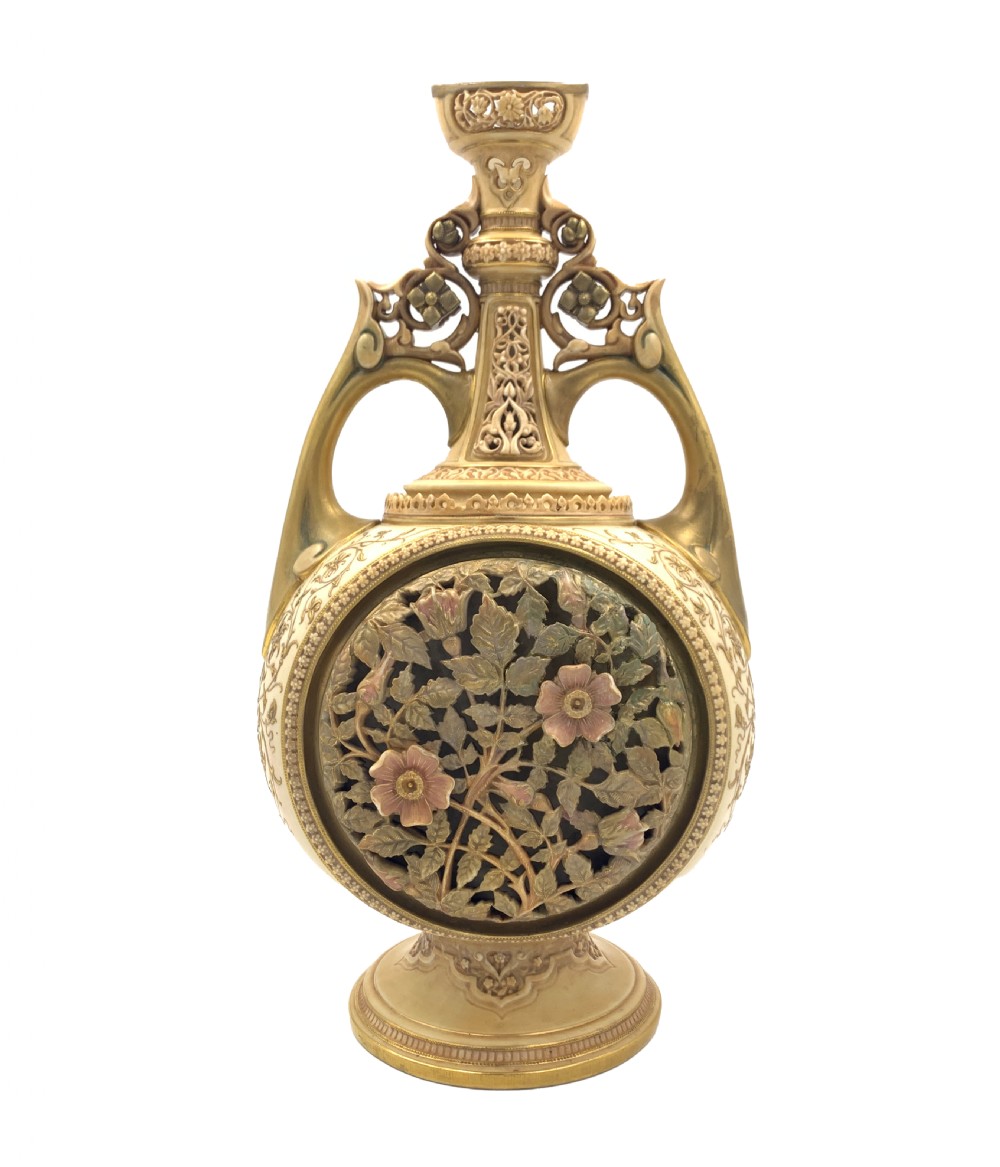 A late 19th-century Royal Worcester porcelain vase featuring twin handles, pierced reticulated panels, gilt accenting, and relief floral decoration on a blush ivory surface. View V