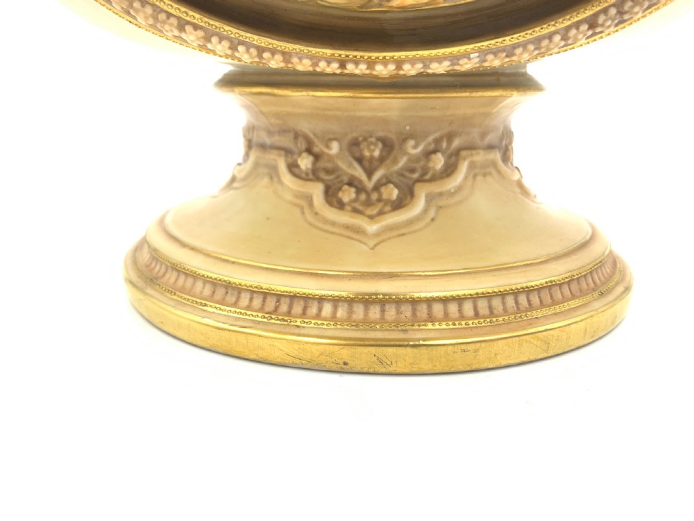A late 19th-century Royal Worcester porcelain vase featuring twin handles, pierced reticulated panels, gilt accenting, and relief floral decoration on a blush ivory surface. View X
