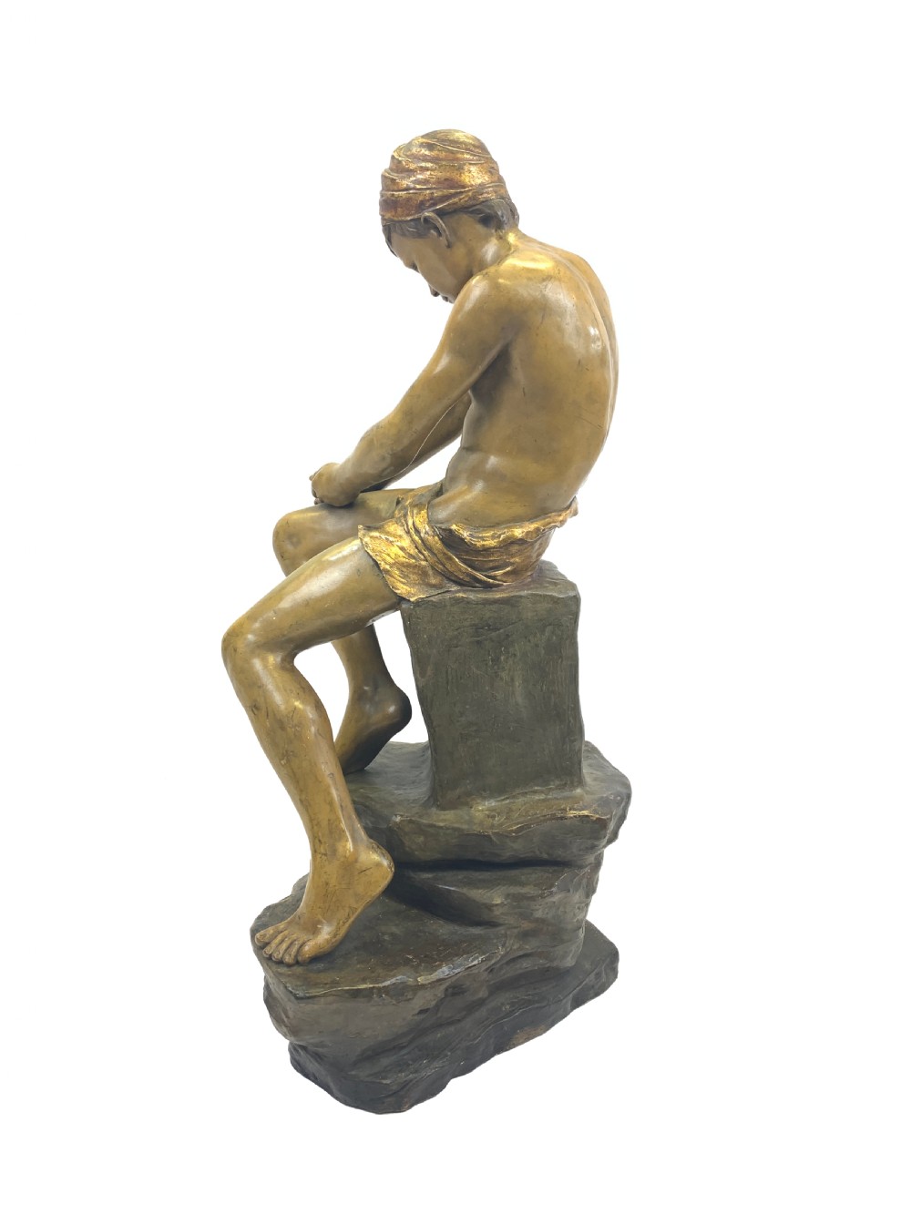 A late 19th-century Goldscheider cold-painted terracotta figure depicting a seated boy with a headscarf on a rocky base, finished in a bronzed metallic glaze. View IV